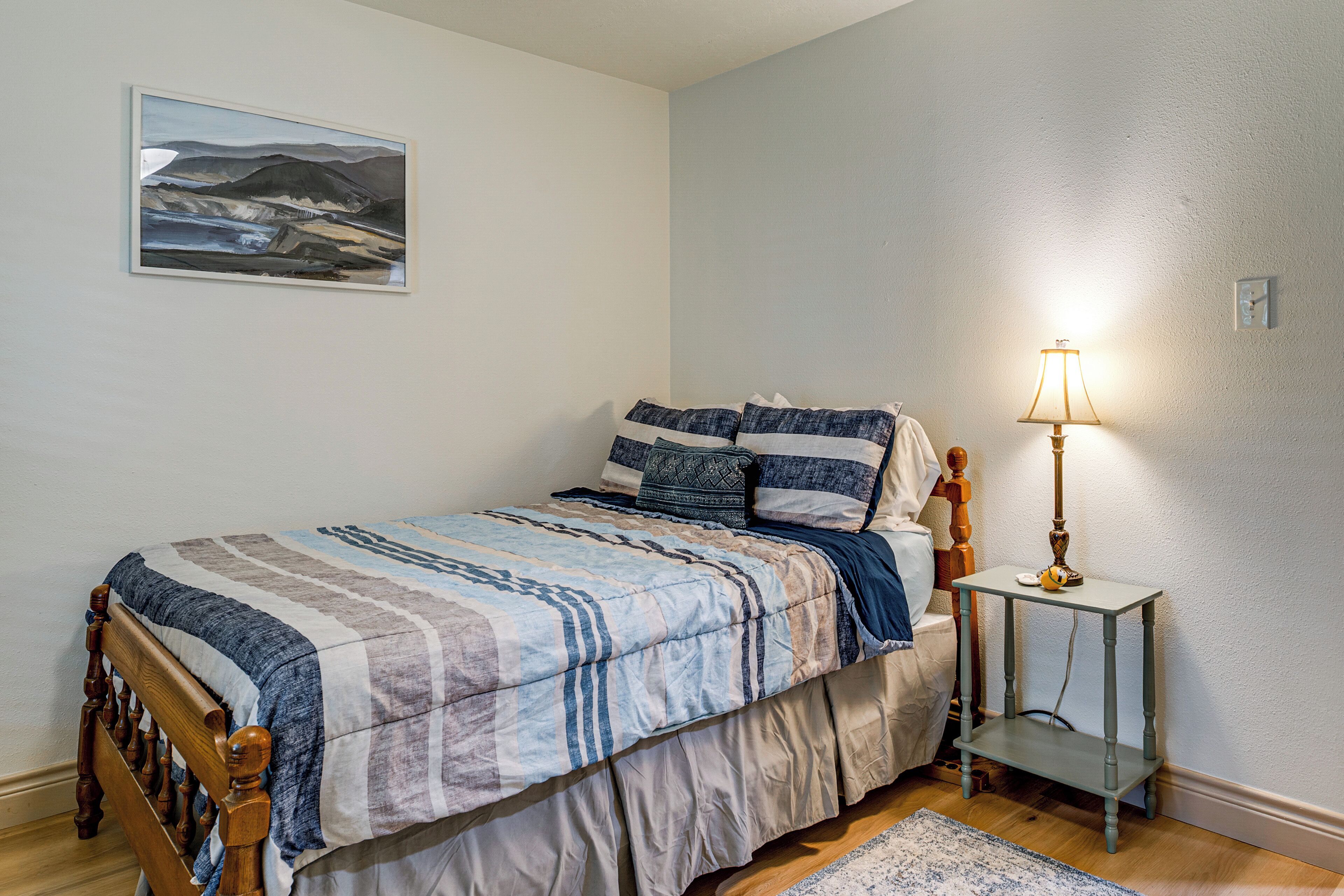 Une chambre à coucher avec un lit, une lampe de chevet, un tapis et un tableau au mur.