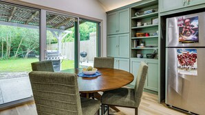 Une cuisine équipée d’une table à manger, de chaises, d’un réfrigérateur et offrant une vue sur l’extérieur.