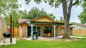 Un jardin avec un patio couvert, un barbecue et un arbre.