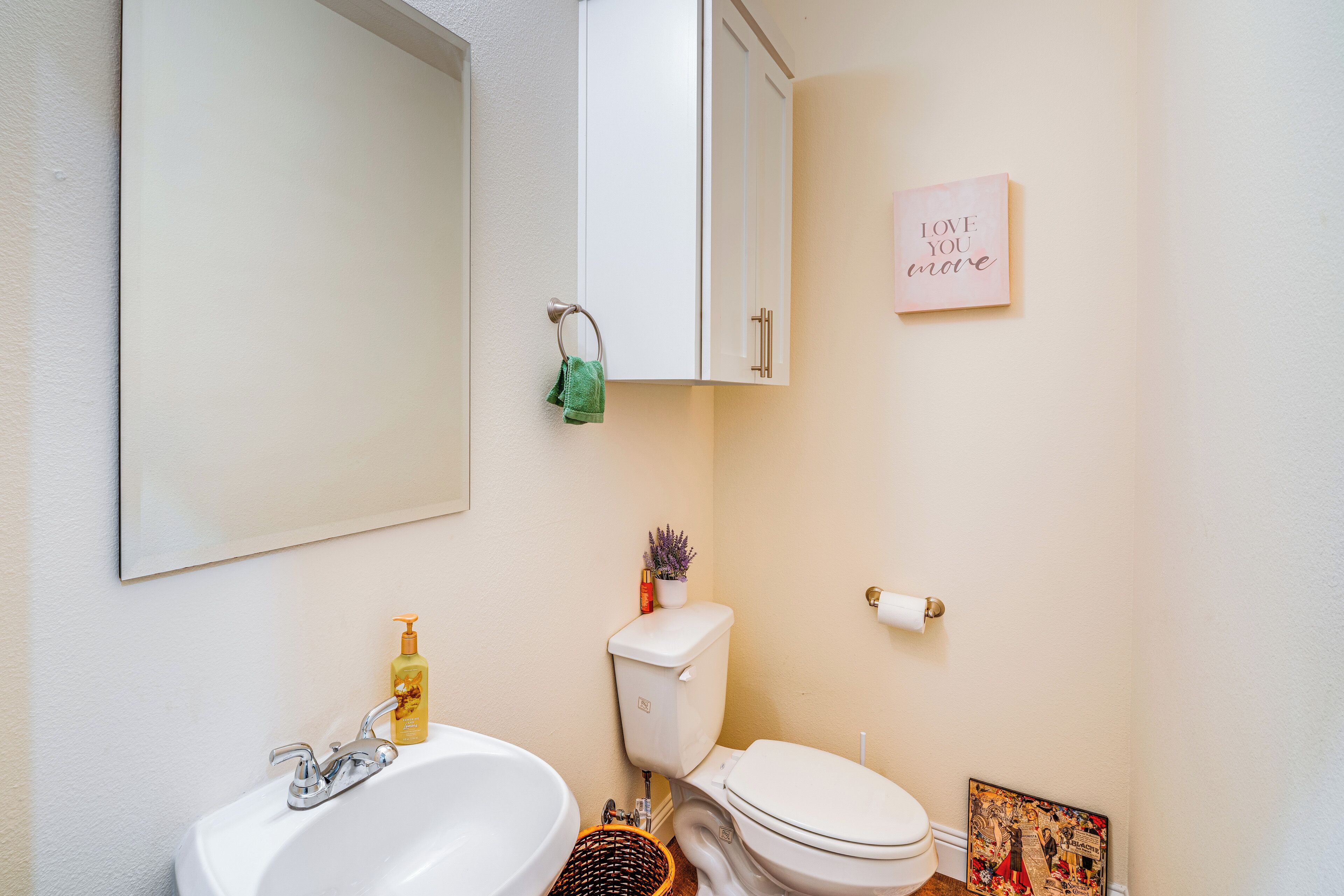 A bathroom with a sink, toilet, and a cabinet above the toilet.