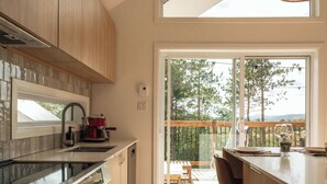 A modern kitchen with a large window, a coffee machine, and a view of the outdoors. - La Selva - Intimate getaway & river access (Sainte-Béatrix)