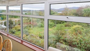 A room with large windows overlooking a garden and a lake.