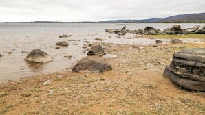 A rocky shoreline with scattered boulders and a calm body of water.