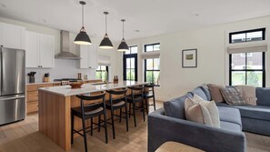 Una cucina moderna con isola centrale, sgabelli da bar e illuminazione a sospensione.