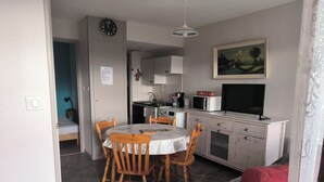 A compact living space with a dining area, kitchenette, and a red sofa. - Charming Studio (Le Tholy)