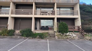 A multi-story building with balconies, a parking lot, and a hillside in the background. - Charming Studio (Le Tholy)