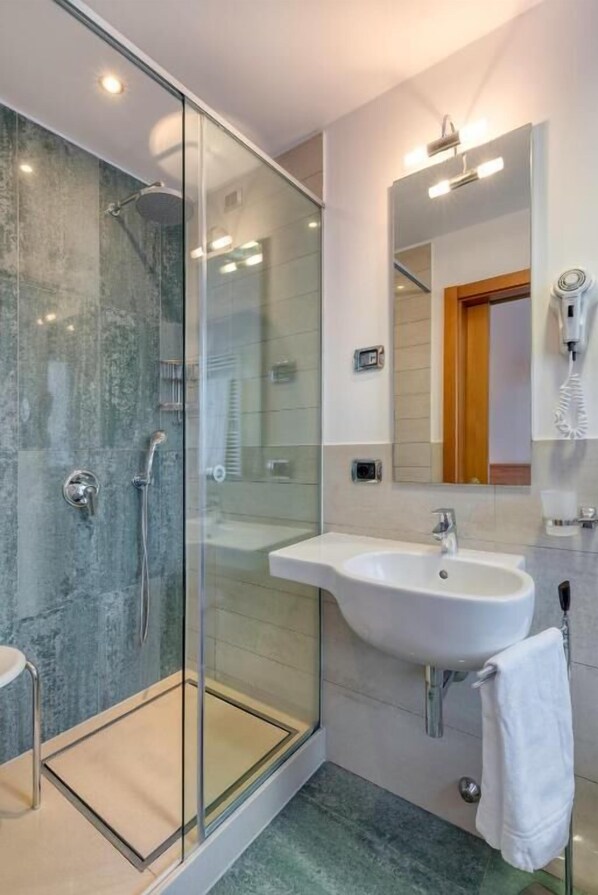 A modern bathroom with a glass-enclosed shower, a white sink, and a mirror above it. - Hotel Sporting Trento (Trento)
