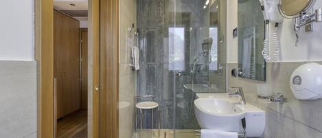 A modern bathroom with a glass shower enclosure, a sink, and a mirror.