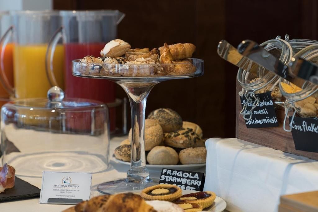 A breakfast buffet with various pastries, a sign for Fragola Strawberry, and a coffee station.