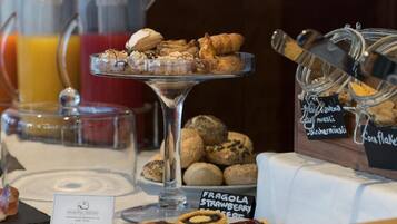 Een ontbijtbuffet met diverse gebakjes, een bord met Fragola Strawberry en een koffiehoek.