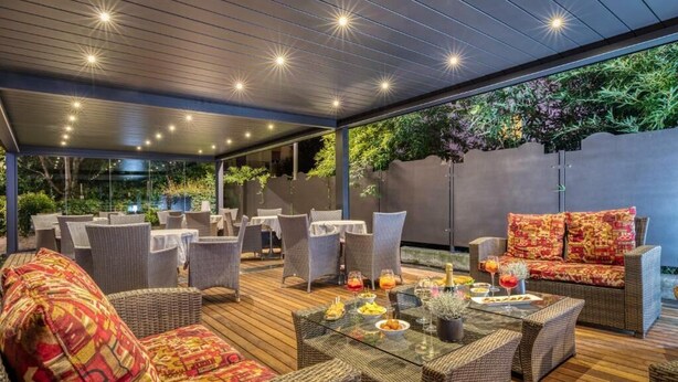 An outdoor patio with wicker furniture, a glass table, and a cushioned sofa. - Hotel Sporting Trento (Trento)
