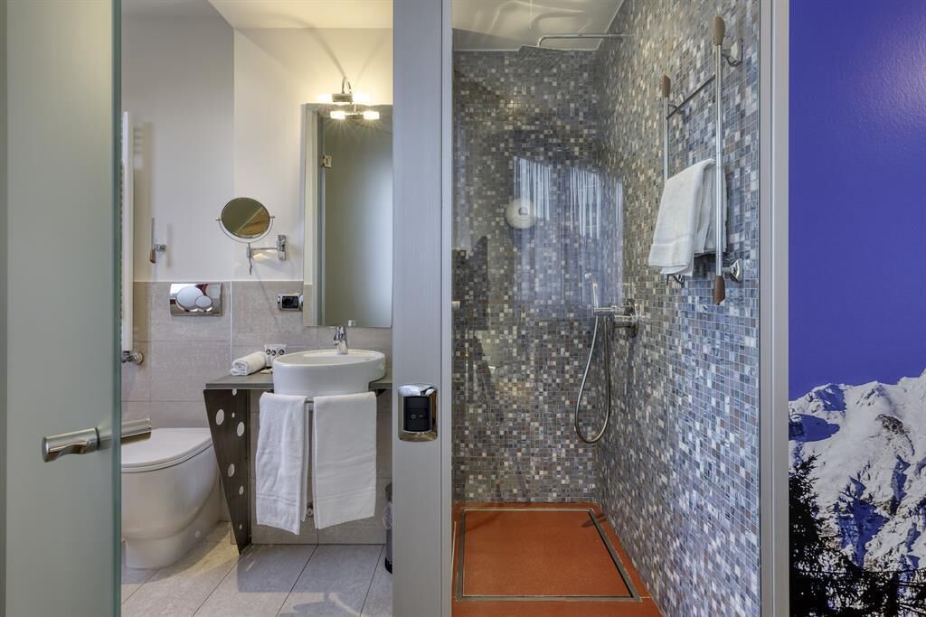 Un baño con inodoro, lavabo, espejo y ducha.