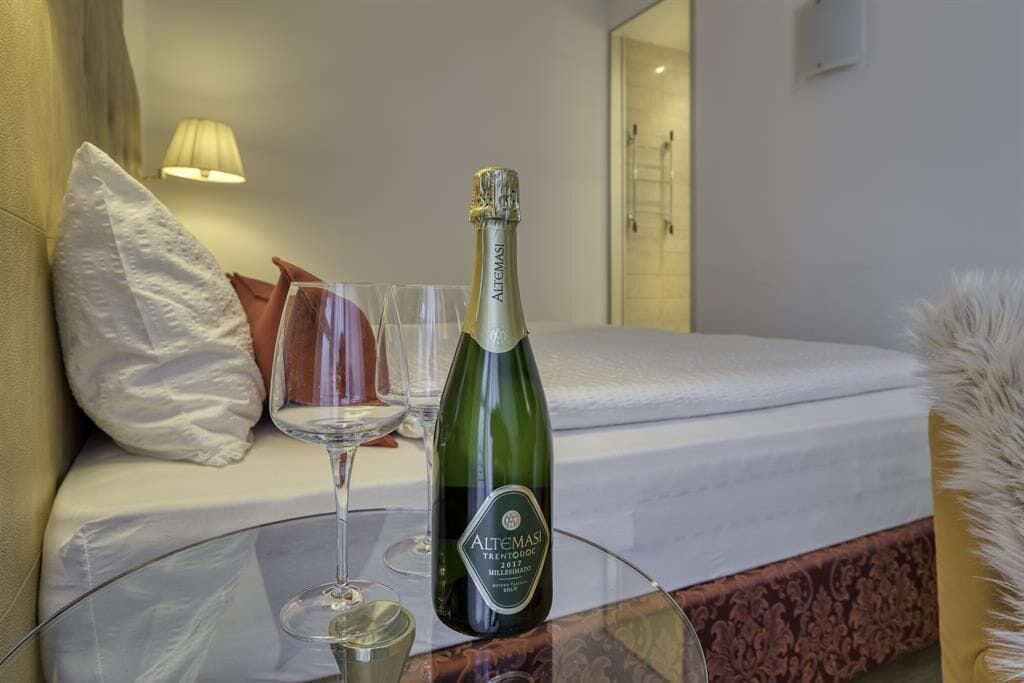 A bottle of Altomasi champagne on a glass table in a hotel room.