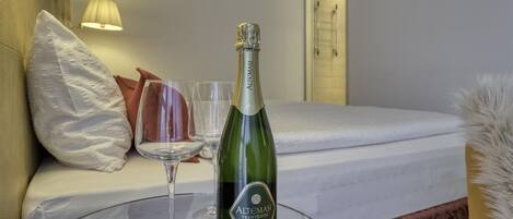 A bottle of Altomasi champagne on a glass table in a hotel room.