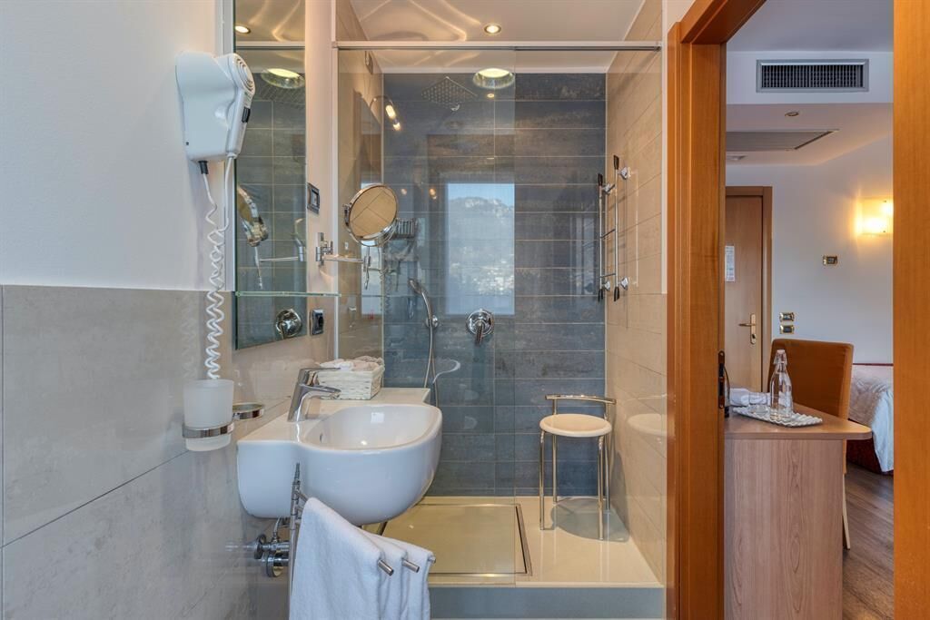 Un baño moderno con un lavamanos grande, cabina de ducha con mampara de cristal y un espejo.