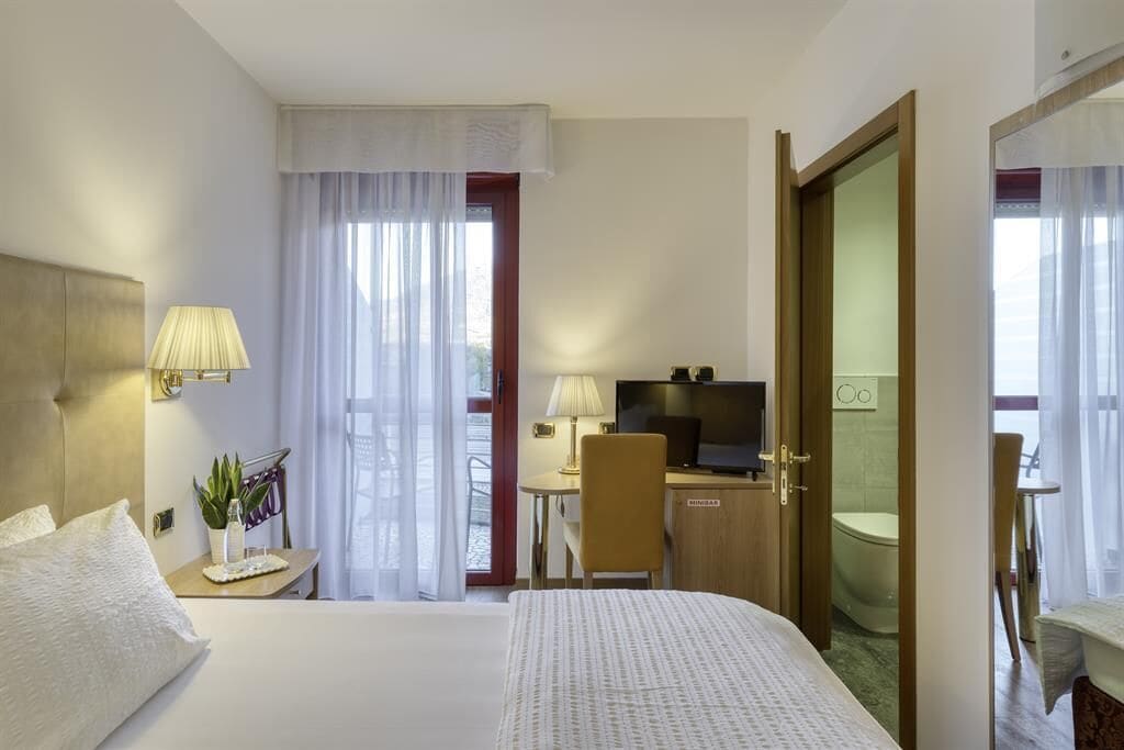 A hotel room with a bed, a desk, a television, and a bathroom.
