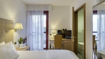 Una camera d'albergo con un letto, una scrivania, una televisione e un bagno.