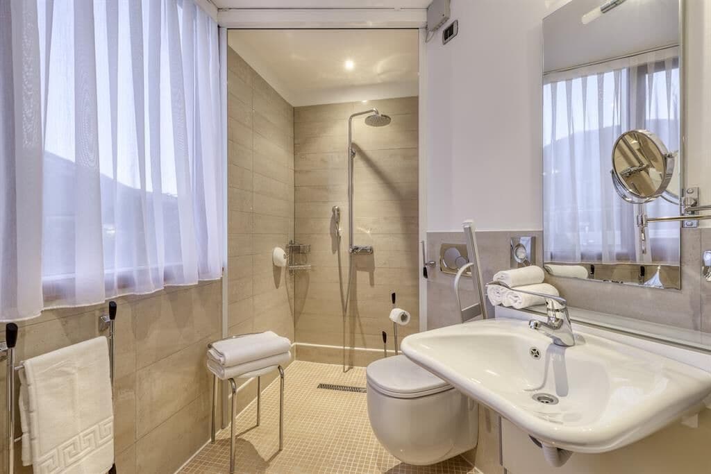Un baño moderno con ducha envuelta en vidrio, un lavabo blanco y un espejo grande.
