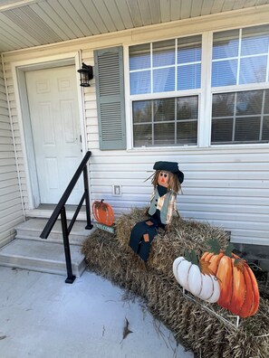 A house with a front porch decorated with hay bales, a scarecrow, and pumpkins. - Charming 2-bedroom house with 2 KING BEDS in Pleasant Poplar Bluff (Poplar Bluff)