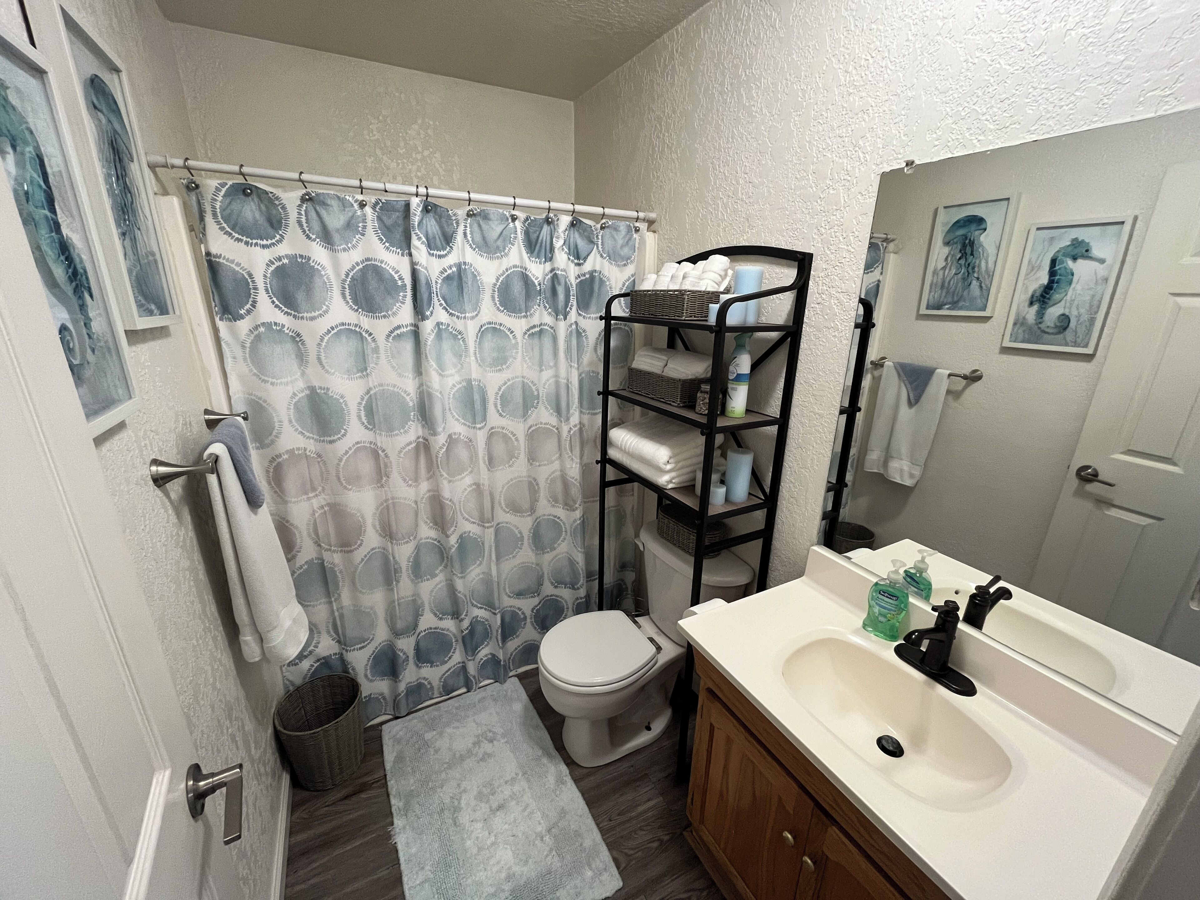 Une salle de bain équipée d’un rideau de douche, de toilettes, d’un lavabo et d’un porte-serviettes.
