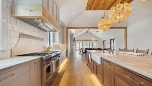 Une cuisine moderne avec des meubles en bois, un grand îlot central et une vue sur la salle à manger.