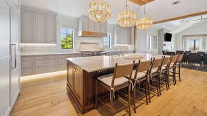 Une cuisine spacieuse dotée d’un grand îlot central, de meubles en bois et de luminaires suspendus.