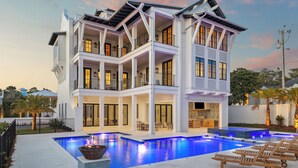 Une maison à plusieurs étages dotée d’une piscine, d’un espace salon extérieur et d’un balcon bien éclairé.