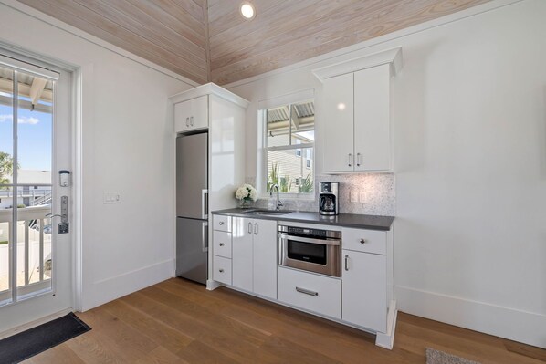 A modern kitchen with white cabinets, stainless steel appliances, and a large window providing natural light. - Gulf Shore Manor|Deeded Beach Access|Private Pool|Golf Cart|Carriage House (Santa Rosa Beach)