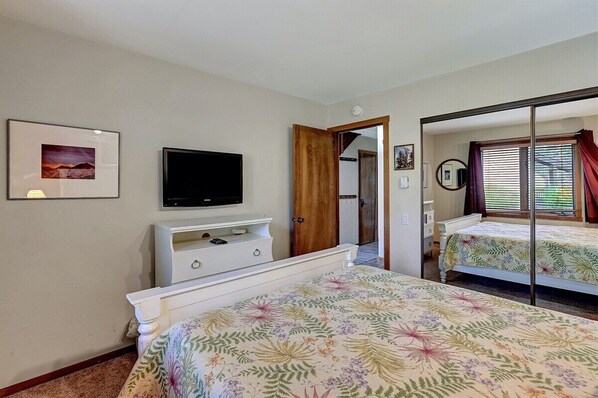 A bedroom with a bed, a TV, a dresser, and a mirror. - Snowcreek 275- Spacious, Pet Friendly (Mammoth Lakes)