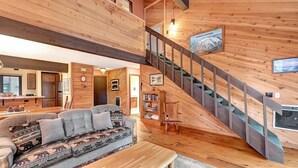 A spacious living area with a wooden staircase, a sofa with patterned cushions, and a bookshelf. - Wildflower 62: Nice Condo, Close to the Green Line (Mammoth Lakes)