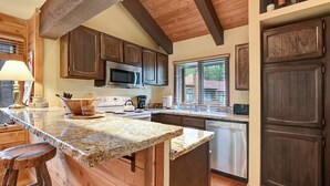 A kitchen with wooden cabinets, granite countertops, a microwave, and a dishwasher. - Wildflower 62: Nice Condo, Close to the Green Line (Mammoth Lakes)