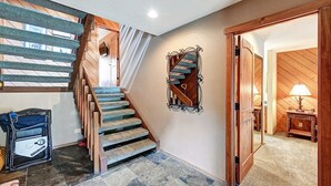 A staircase with wooden steps and blue carpet, leading to a room with a wooden door and a lamp. - Snowcreek 476- Nice Spacious Townhouse (Mammoth Lakes)