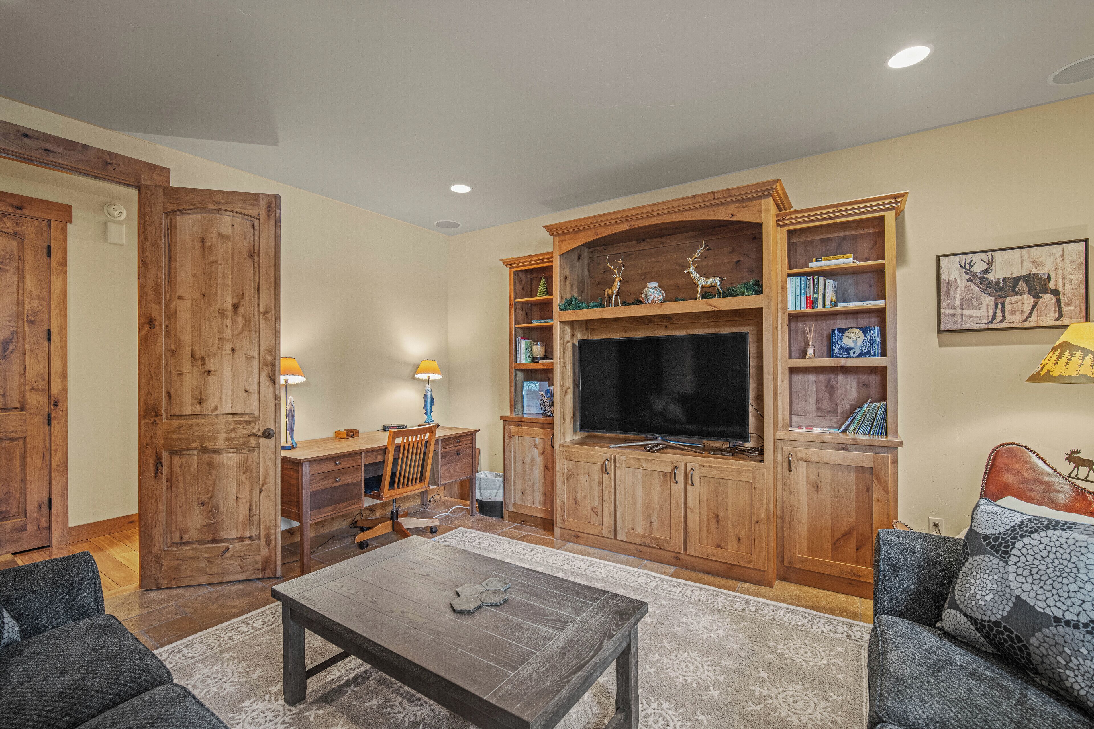 A living room with a wooden entertainment center, a flat-screen TV, and a fireplace.