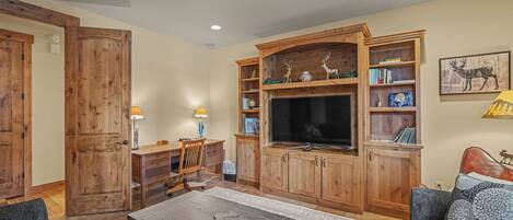 A living room with a wooden entertainment center, a flat-screen TV, and a fireplace.
