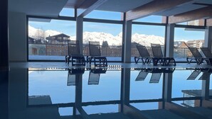 An indoor swimming pool with clear views of snow-capped mountains through large windows. - 3 Bedroom Apartment Nendaz, Switzerland. 5 mins walk to tracouet gondala. (Nendaz)