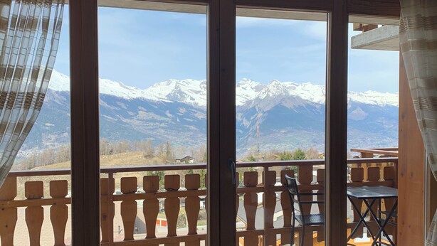 A room with a large sliding glass door leading to a balcony with a mountain view. - 3 Bedroom Apartment Nendaz, Switzerland. 5 mins walk to tracouet gondala. (Nendaz)
