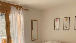 A wooden bed with white bedding in a room with a large mirror and two framed floral paintings on the wall. - 3 Bedroom Apartment Nendaz, Switzerland. 5 mins walk to tracouet gondala. (Nendaz)
