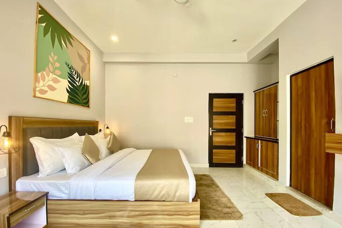 A bedroom with a bed, wooden wardrobe, and a painting on the wall.