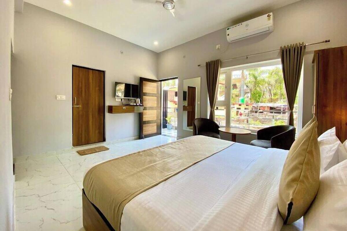 A modern hotel room with a large bed, a ceiling fan, an air conditioning unit, a TV, and a view of the outdoors.