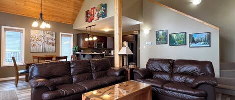 A spacious living room with leather sofas, a wooden coffee table, and a dining area with a table and chairs.