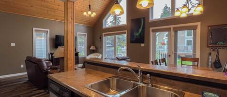 A kitchen with a double sink, wooden ceiling, and pendant lighting.