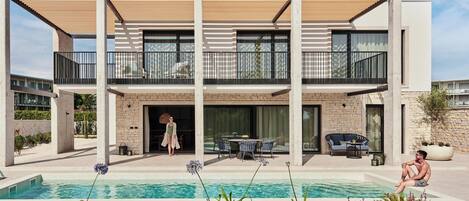 Uma casa moderna de dois andares com piscina, área de estar externa e varanda.