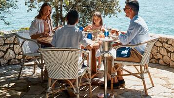Enjoy a tranquil meal with a view of the water and surrounding hills from this serene outdoor dining area.