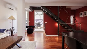 A modern living room with a wooden floor, a sofa, a coffee table, and a staircase leading to a balcony. - Dream Vacation at Casa Vicki (Almeria)