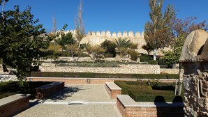 A courtyard with a stone wall, a brick building, and a view of a historical fortification in the background. - Dream Vacation at Casa Vicki (Almeria)
