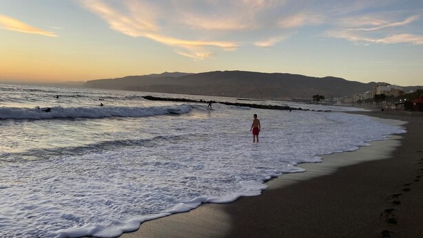 A beach with waves, a person in red shorts, and distant mountains. - Dream Vacation at Casa Vicki (Almeria)
