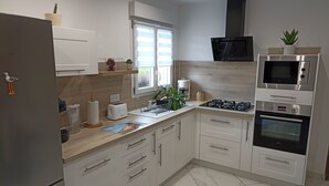 A modern kitchen with white cabinets, a stainless steel refrigerator, a microwave, an oven, and a sink. - Country cottage near the Baie de Somme - Le Clos de R & R (Cambron)