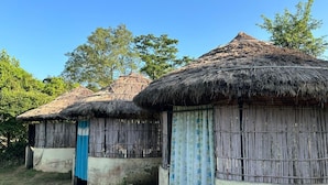 Une rangée de huttes aux toits de chaume, aux murs en bois et à la porte bleue.