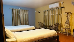 Une chambre avec deux lits, un ventilateur de plafond et une fenêtre avec des rideaux.