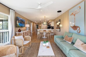 A spacious living area with a dining table, sofas, and a large window. - Palm Bay, Condo, Beach, Golf Cart, Pools (Miramar Beach)